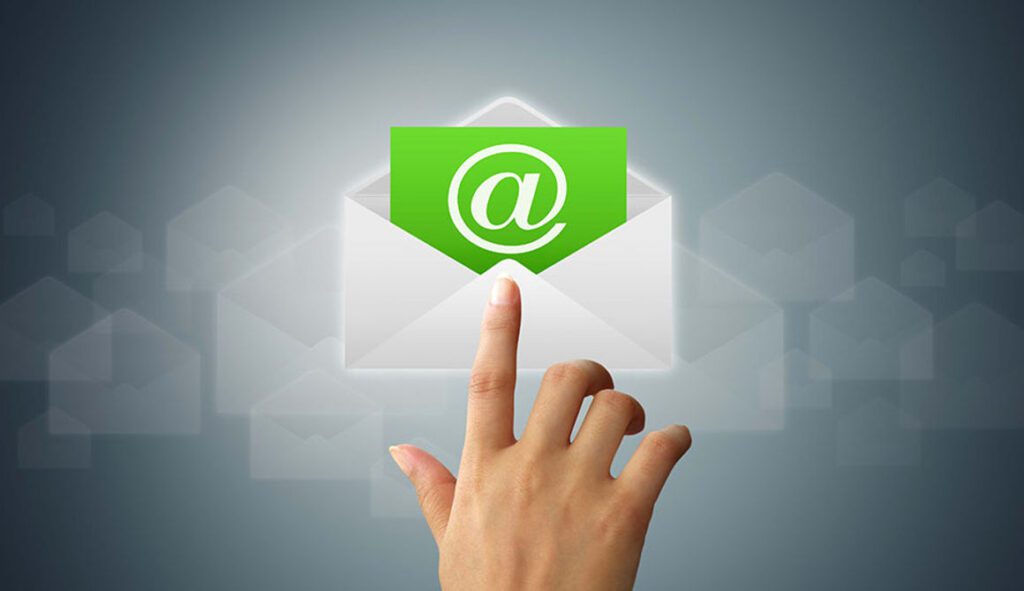 Hand pointing at a green email icon emerging from an envelope.