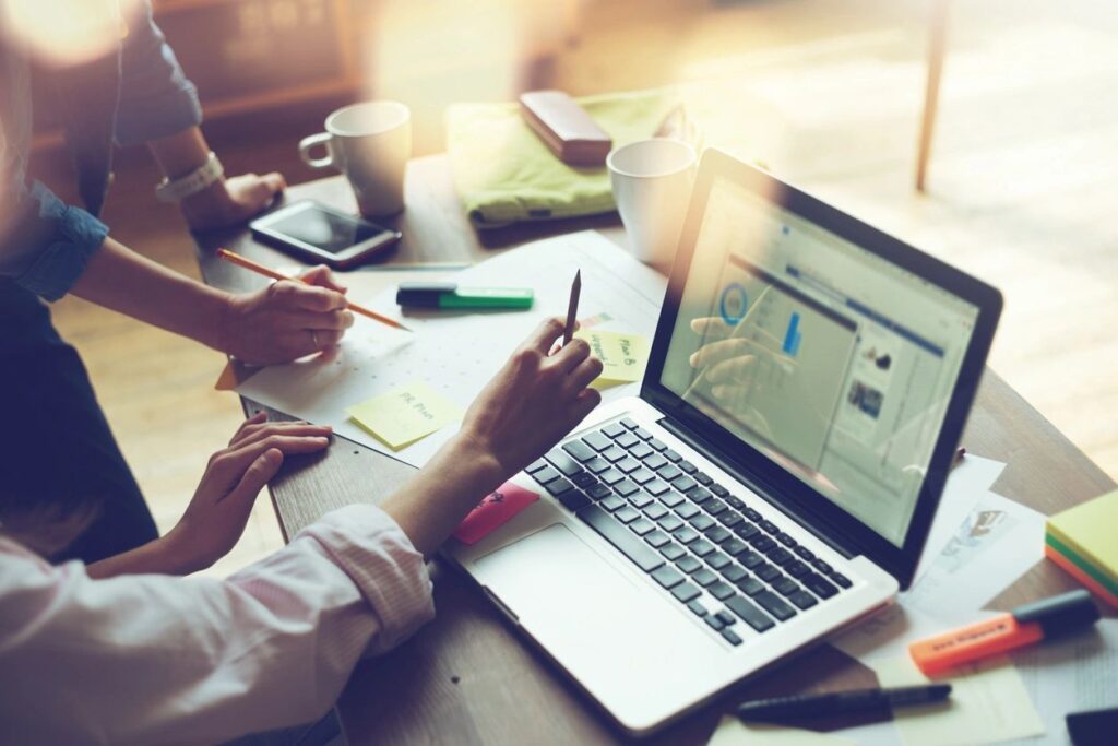 People collaborating on a laptop in a bright office setting.