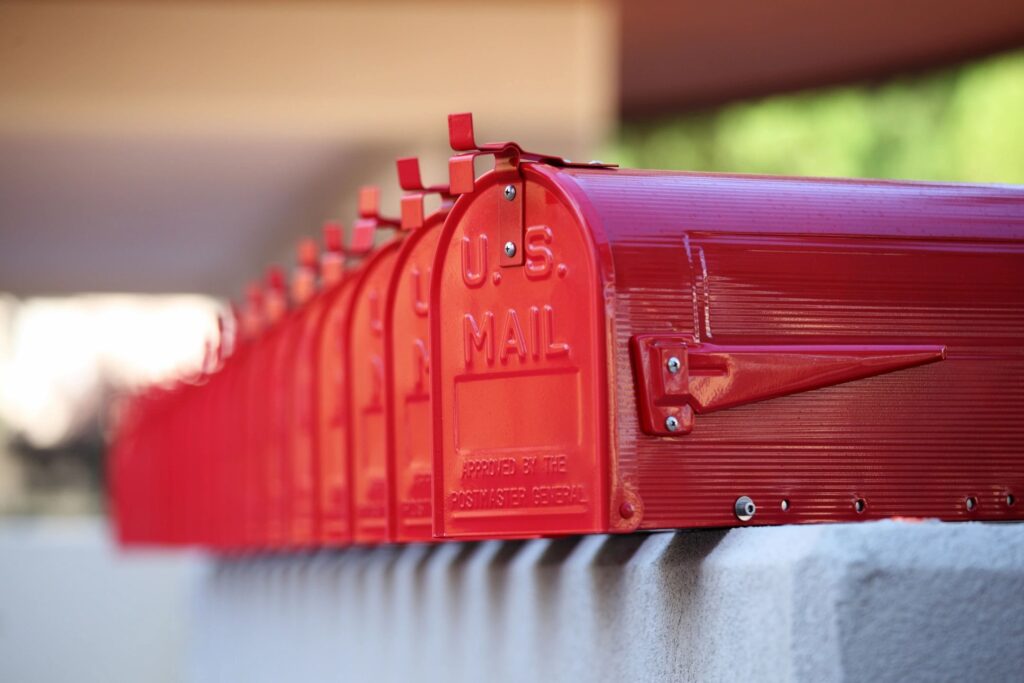 Row of red USPS mailboxes outdoors on a sunny day.