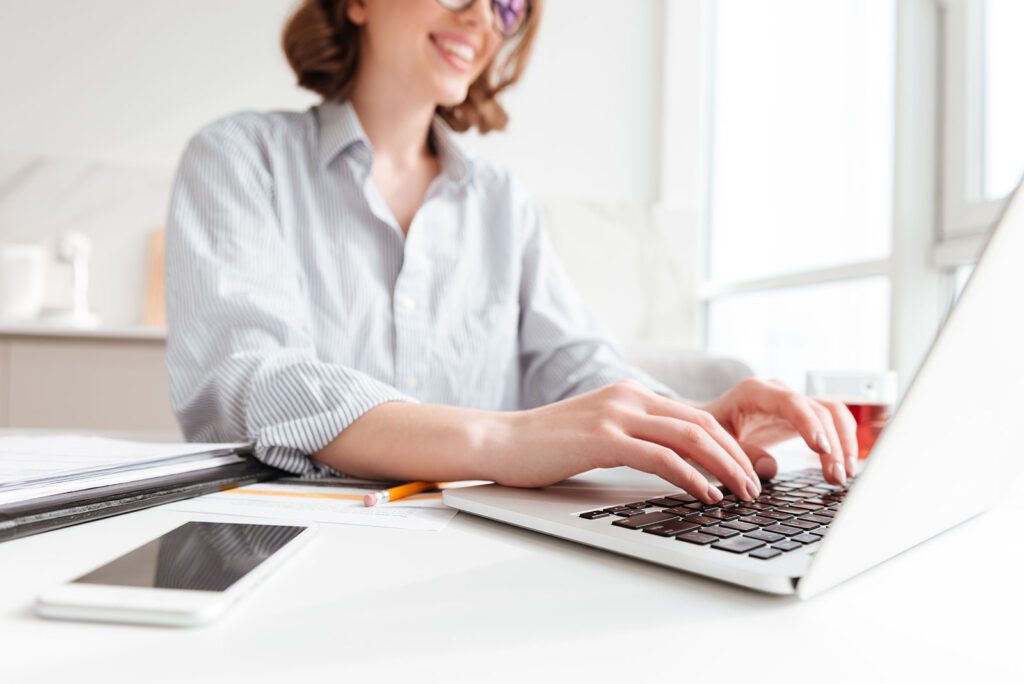 Person typing on a laptop keyboard with a smile.