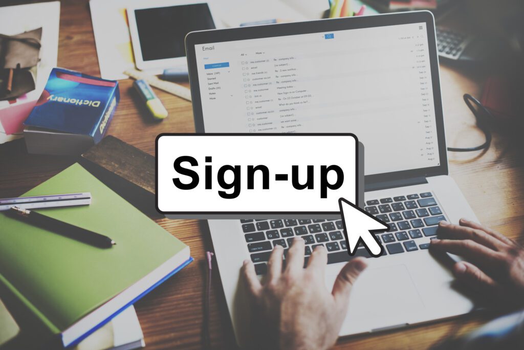 Person signing up on a website using a laptop at a desk.