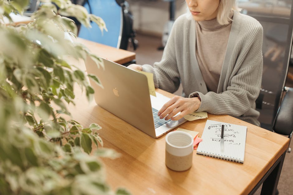 Person working on a laptop with a notebook and coffee nearby.