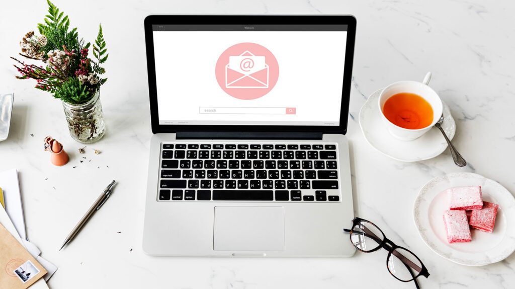 Laptop displaying an email notification on screen with glasses and a cup of tea nearby.