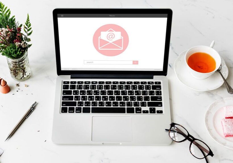 Laptop displaying an email notification on screen with glasses and a cup of tea nearby.