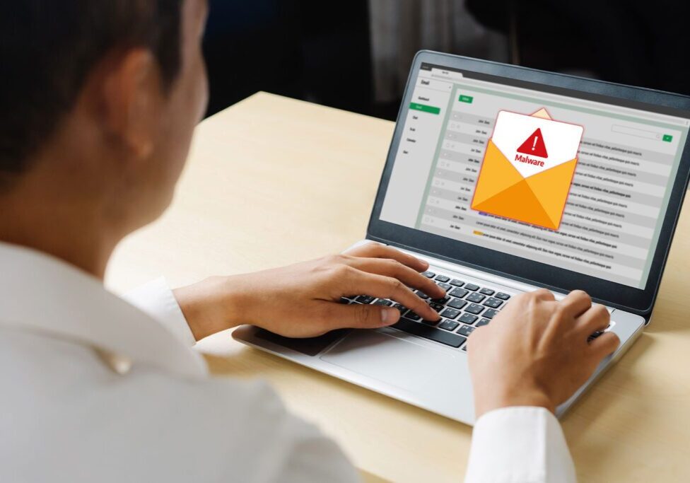 Person checking an email with a warning alert on a laptop.