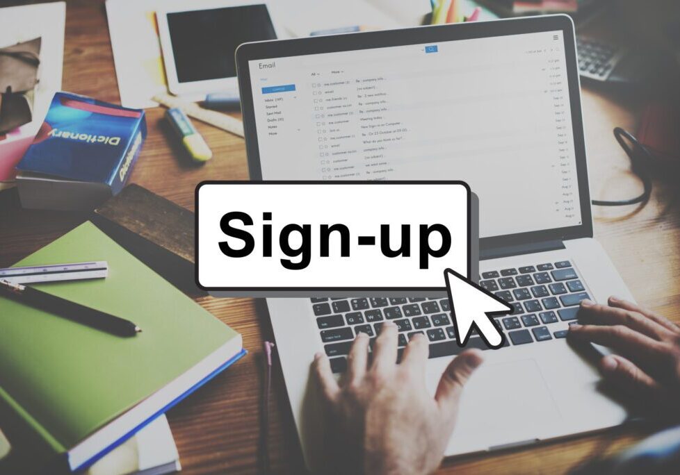 Person signing up on a website using a laptop at a desk.