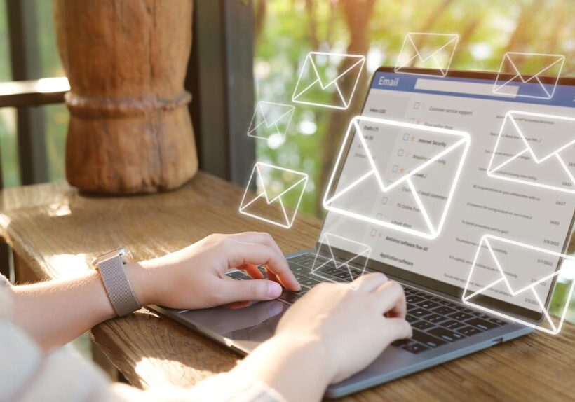Person typing on laptop with digital email icons floating above.