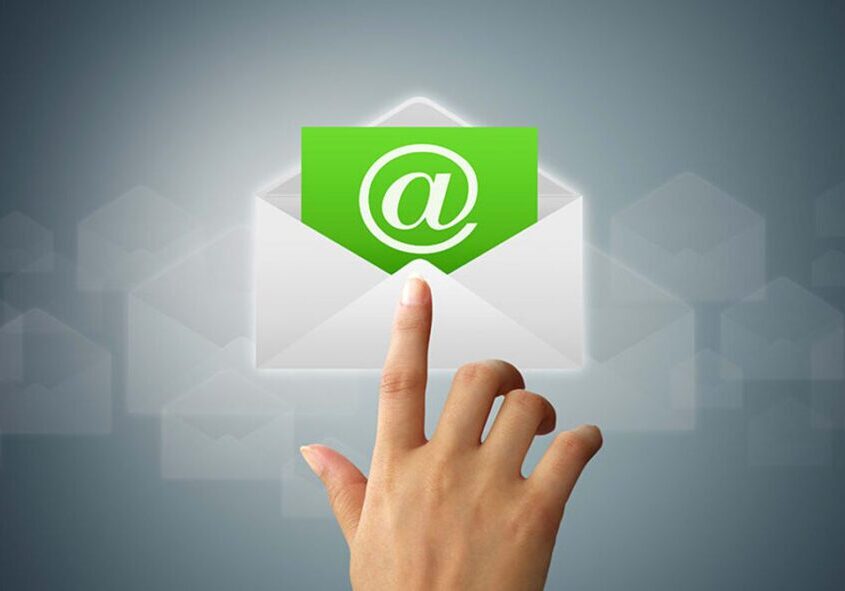 Hand pointing at a green email icon emerging from an envelope.