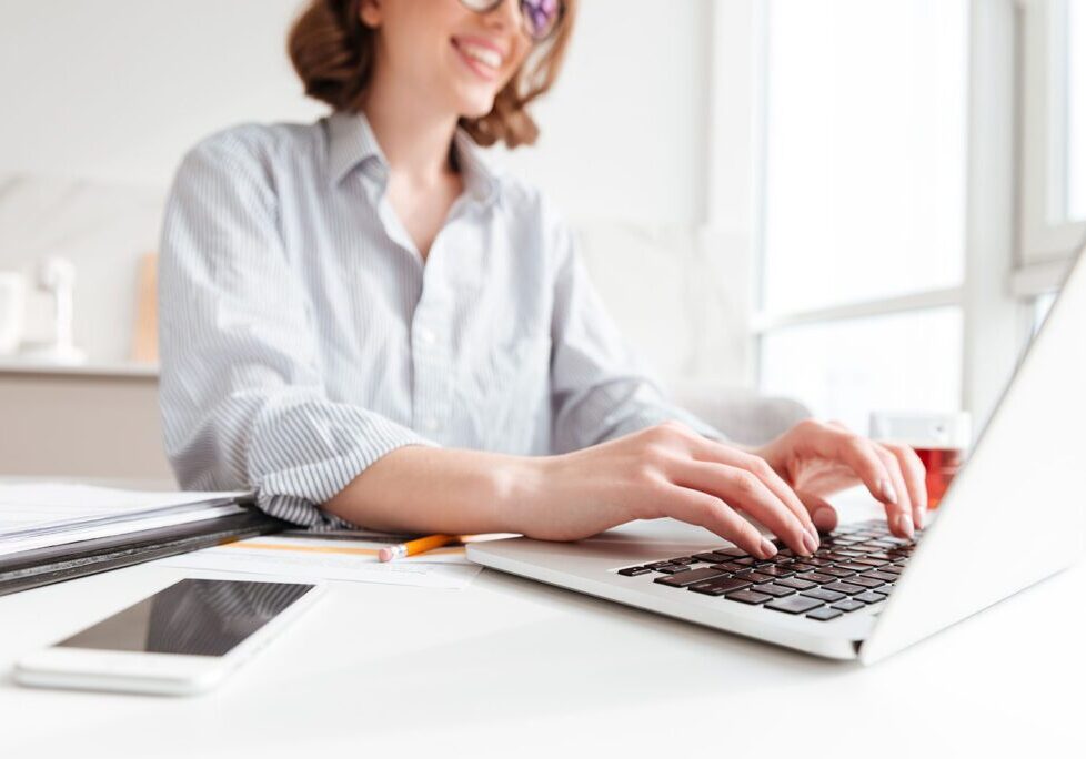 Person typing on a laptop keyboard with a smile.