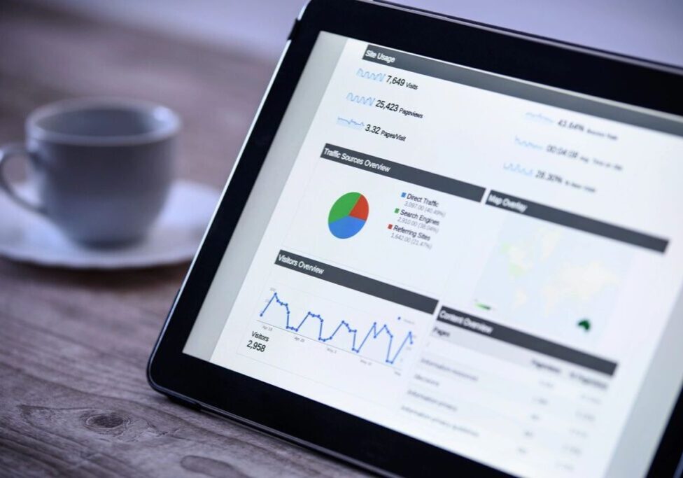 Tablet displaying data analytics and charts with a coffee cup nearby.