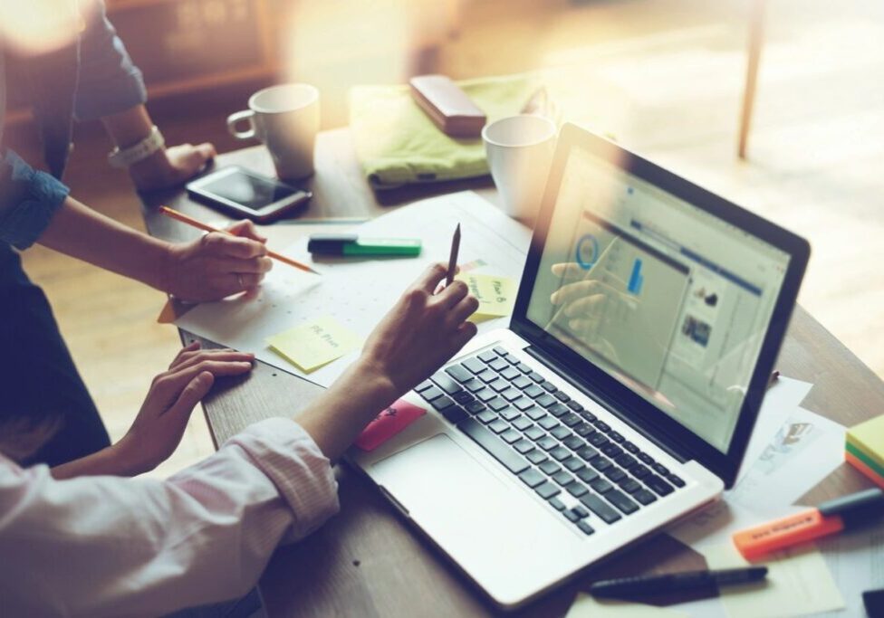People collaborating on a laptop in a bright office setting.